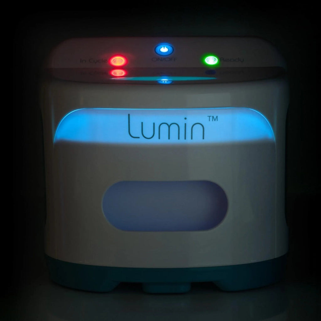 The lumin shown in low lighting - blue UV light glows through a small partition of the front of the drawer, an illuminated red in cycle light, illuminated green ready tatus light, and illuminated blue on/off button light.