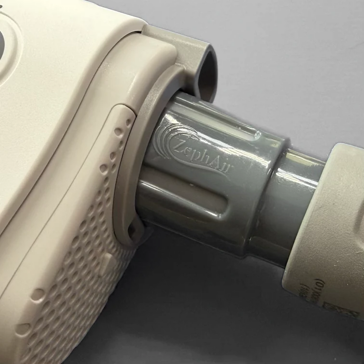 Detail shot of a grey ZephAir adapter connected to a white cpap.com travel machine.