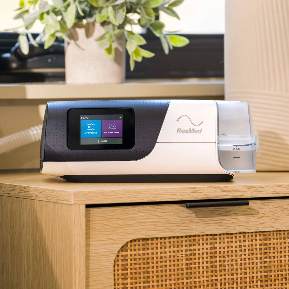 ResMed AirSense 11 CPAP machine with digital display and water chamber on a wooden bedside table.
