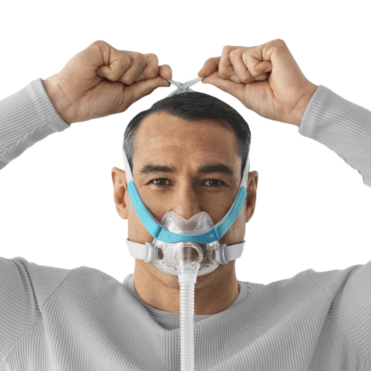 Image of a man wearing a F&P Evora Full Face Mask and adjusting the size of its headgear by pulling the ends on top of his head.