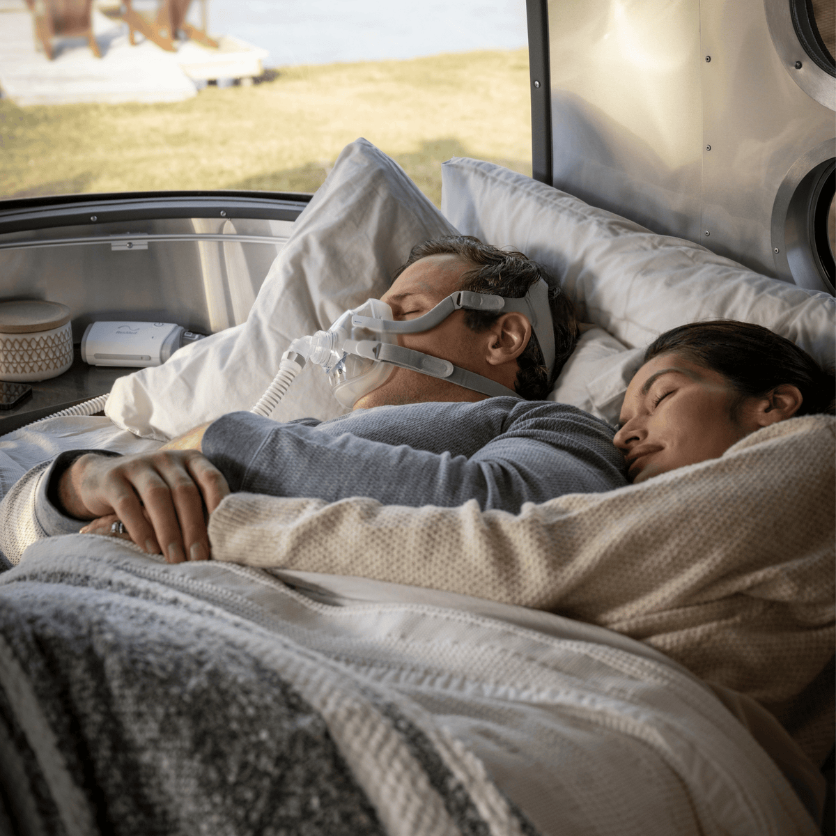 Man using ResMed AirMini travel CPAP with AirFit F20 mask while sleeping in a camper van.