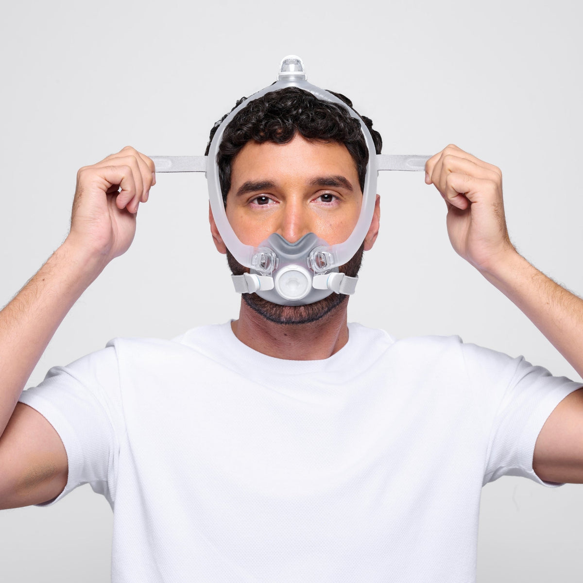 a man wearing the airtouch f30i full face cpap mask adjusts the upper headgear straps