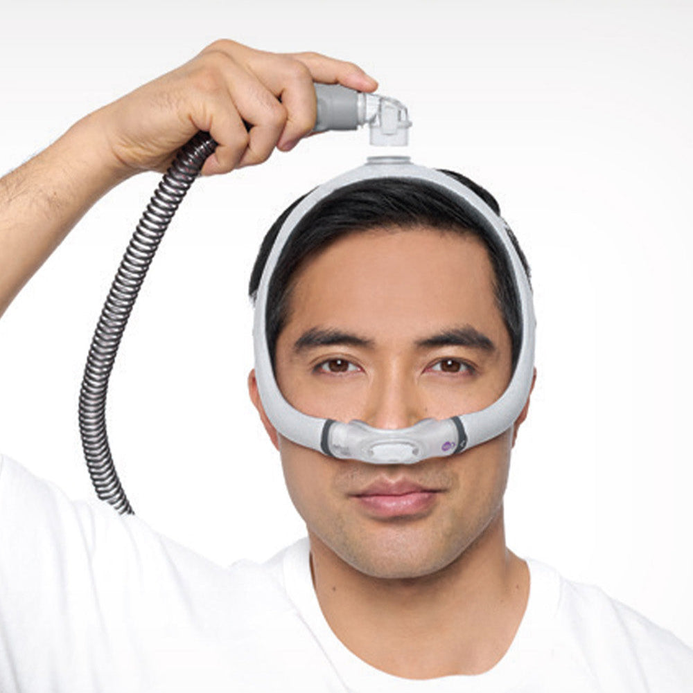 A man wearing the ResMed AirTouch N30i nasal CPAP mask, demonstrating its top-of-head tube connection by holding the hose above his head.
