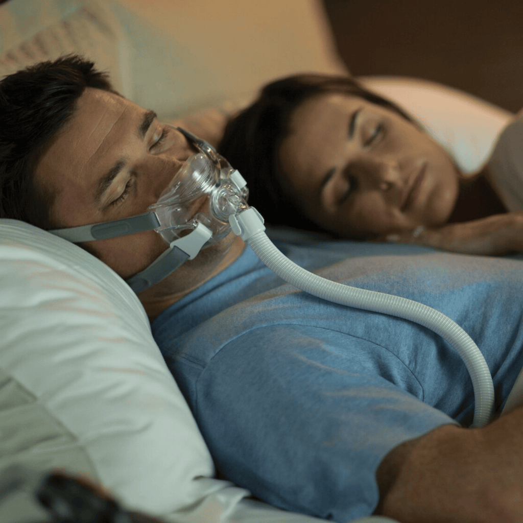 man sleeping in amara view mask with his wife nearby