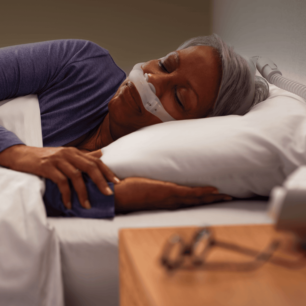 a woman sleeps soundly while wearing the dreamwear nasal pillow cpap mask