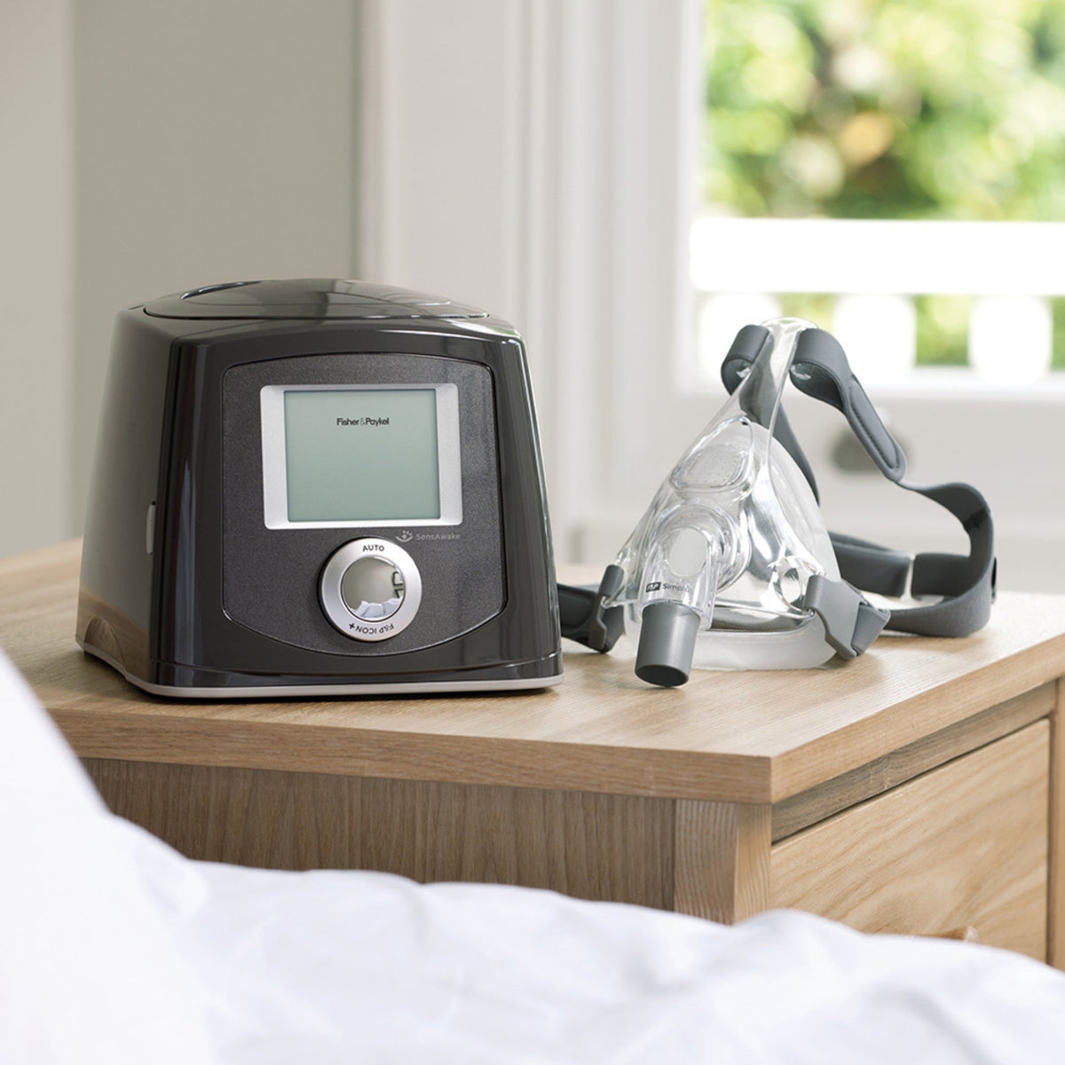 F&P simplus mask resting on a nightstand beside F&P Icon CPAP machine