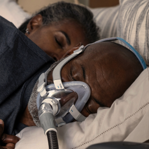 Man sleeping with ResMed AirFit F20 full face CPAP mask and headgear.